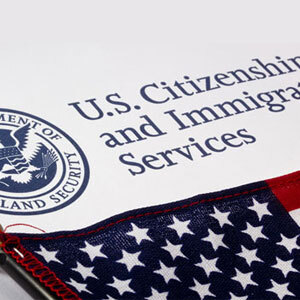 Logo of US Citizenship and Immigration Services, featuring American flag - Serving Immigrants